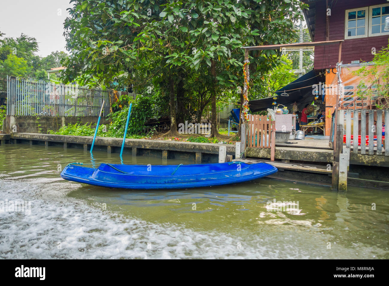 Veduta esterna di plastica blu piccola barca in riva al fiume e a yai canal o Khlong Bang Luang in Thailandia Foto Stock