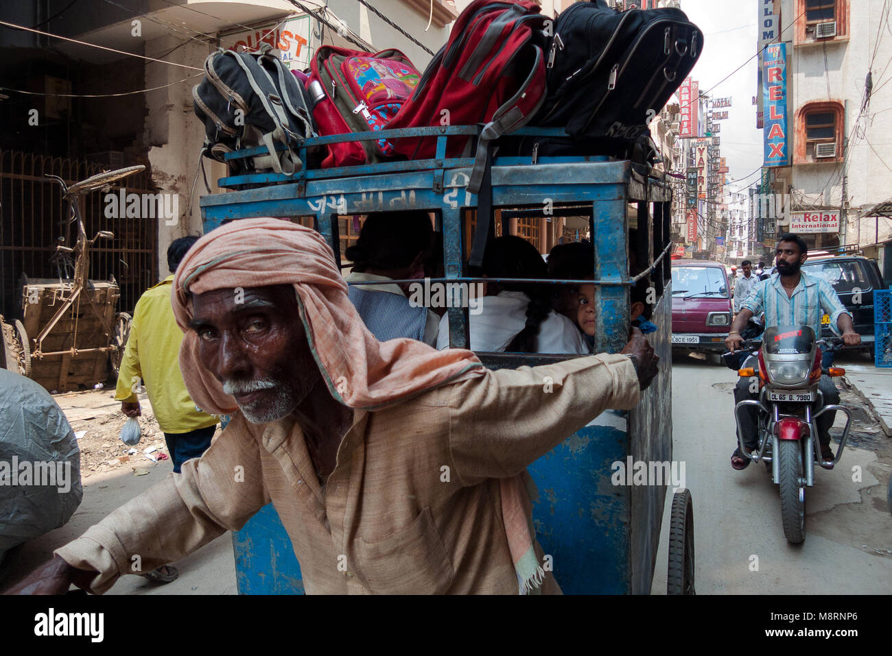 New Delhi, India: un uomo tira un rickshaw piena di indiani scolari presso la scuola uscire a Nuova Delhi. Foto Stock