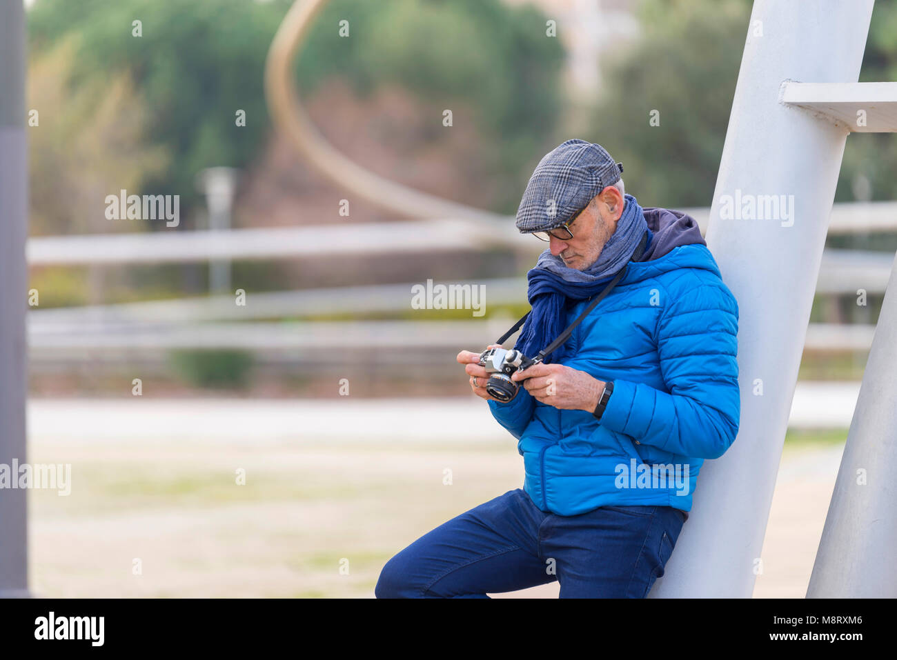 Uomo che guarda la fotocamera mentre appoggiata sul palo in posizione di parcheggio Foto Stock
