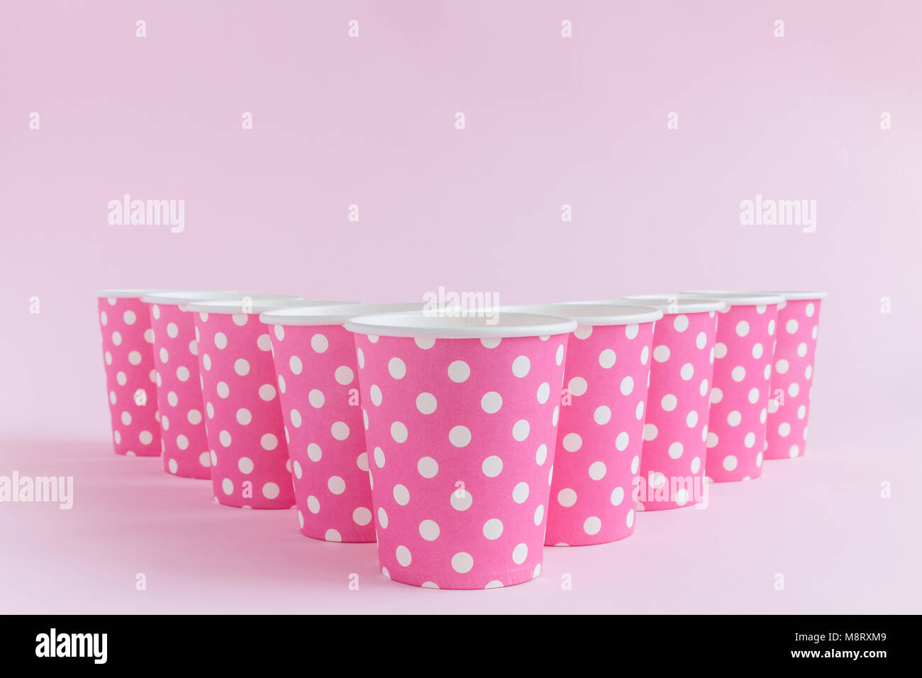 Bicchieri di carta polka design contro di rosa pastello minima di sfondo concetto creativo Foto Stock