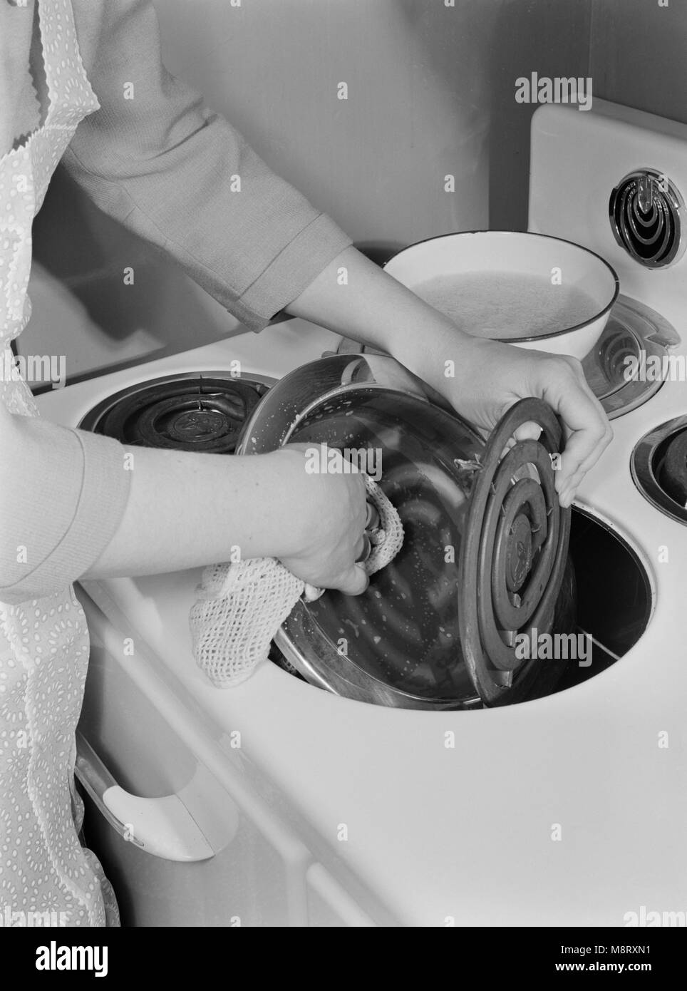 Donna di pulizia Stufa elettrica con acqua e sapone per mantenerlo in funzione al suo meglio, come stufe nuove e altri beni durevoli saranno scarse durante sforzo bellico, Ann Rosener, Ufficio di informazione di guerra, Febbraio 1942 Foto Stock