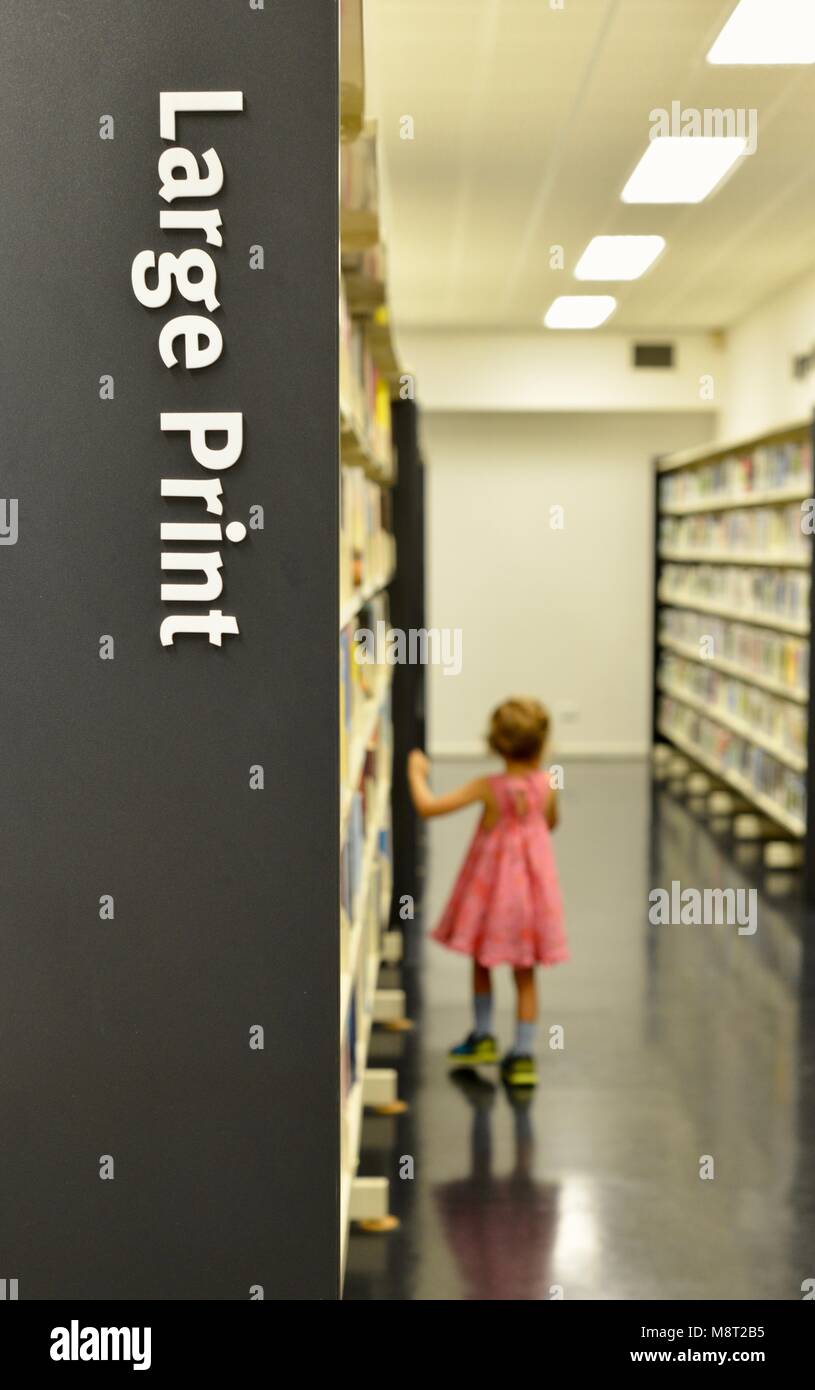 Bambino Piccolo passeggiate passato uno scaffale in una libreria, CityLibraries Aitkenvale, Townsville Queensland, Australia Foto Stock