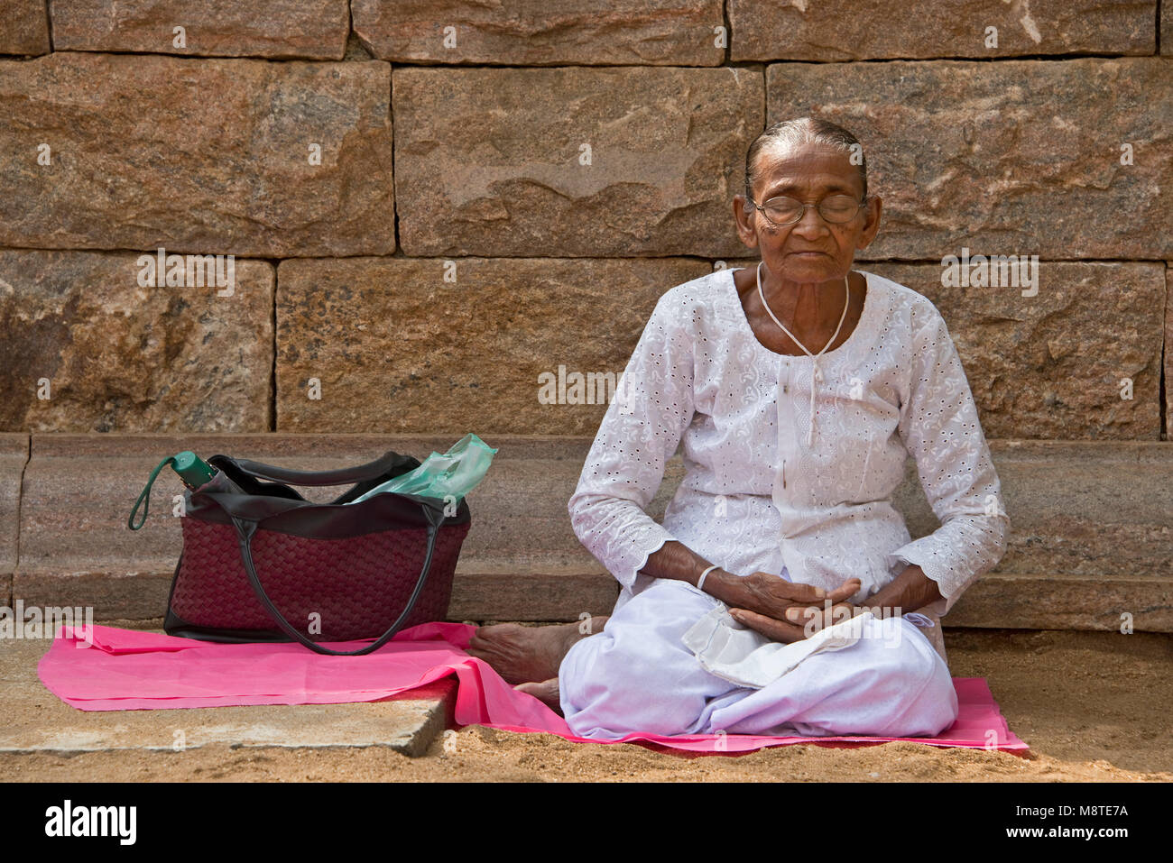 Un anziano dello Sri Lanka donna, pregando e meditando a Jaya Sri Maha Bodhi in Anuradhapura, Sri Lanka. Foto Stock