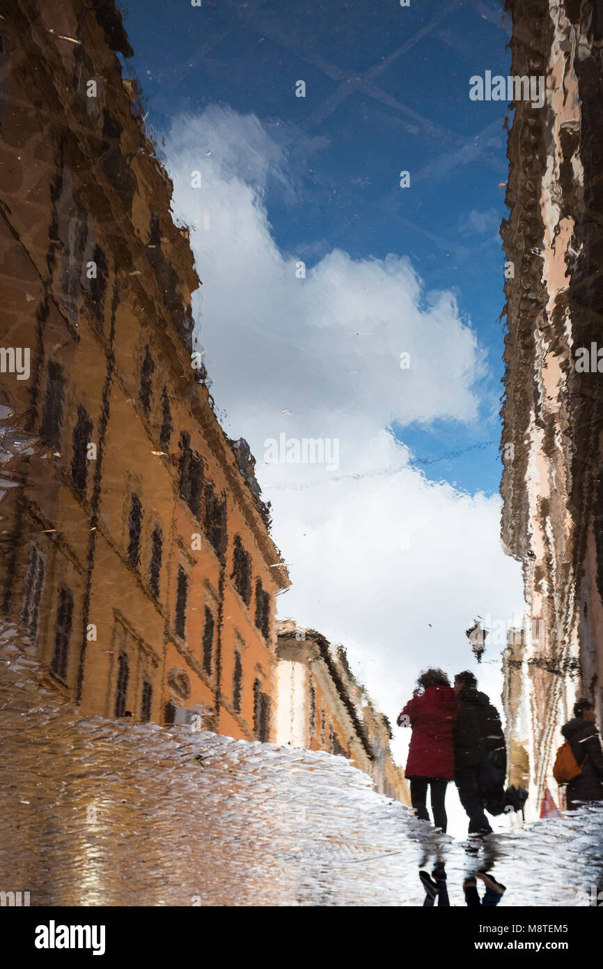 Due persone si riflette in una grande pozza dopo una doccia di pioggia, Roma, Italia Foto Stock