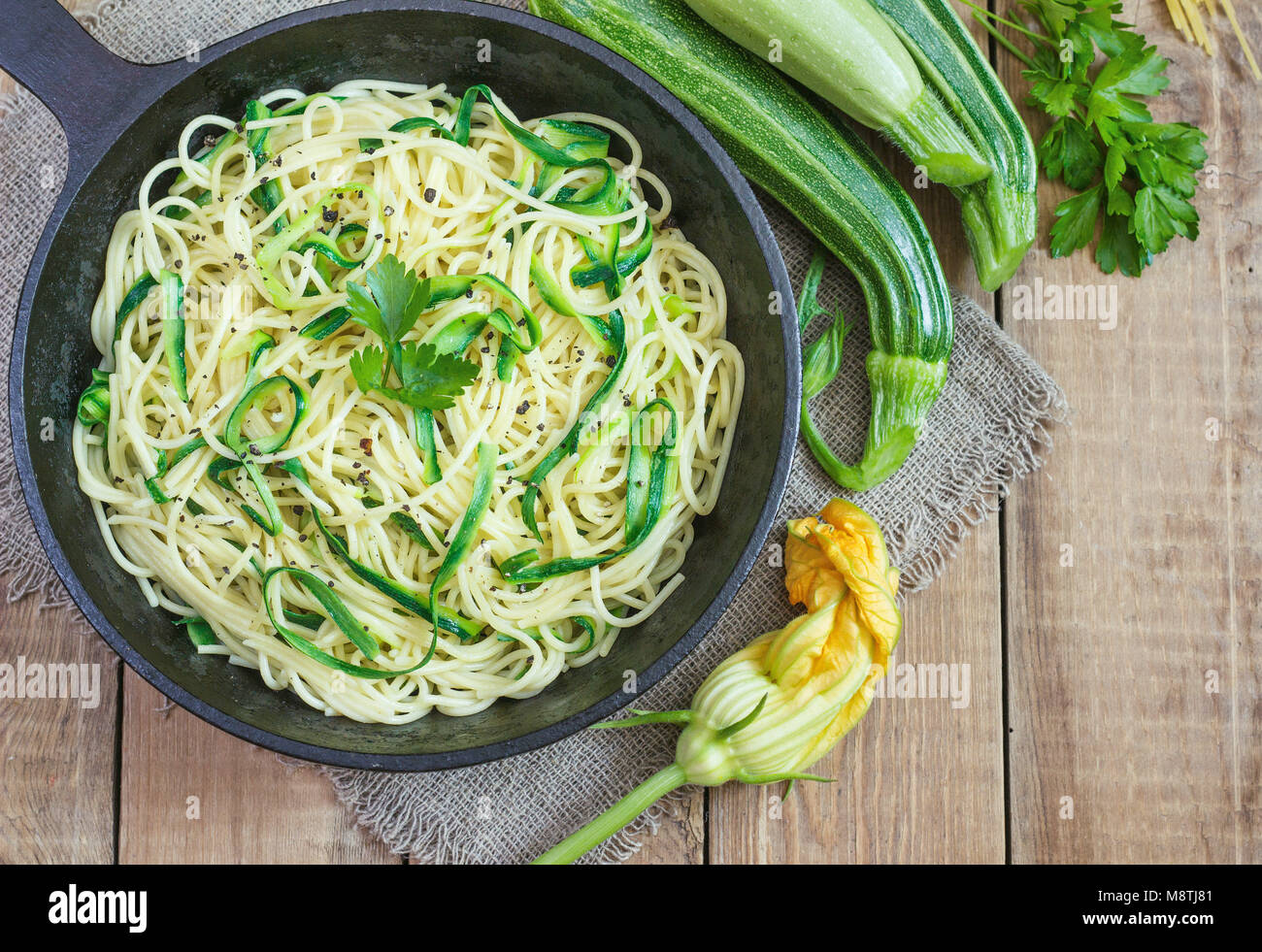 Pasta con le zucchine sul legno scuro in background di ghisa padella . Spaghetti da agricoltura biologica farine integrali. Foto Stock