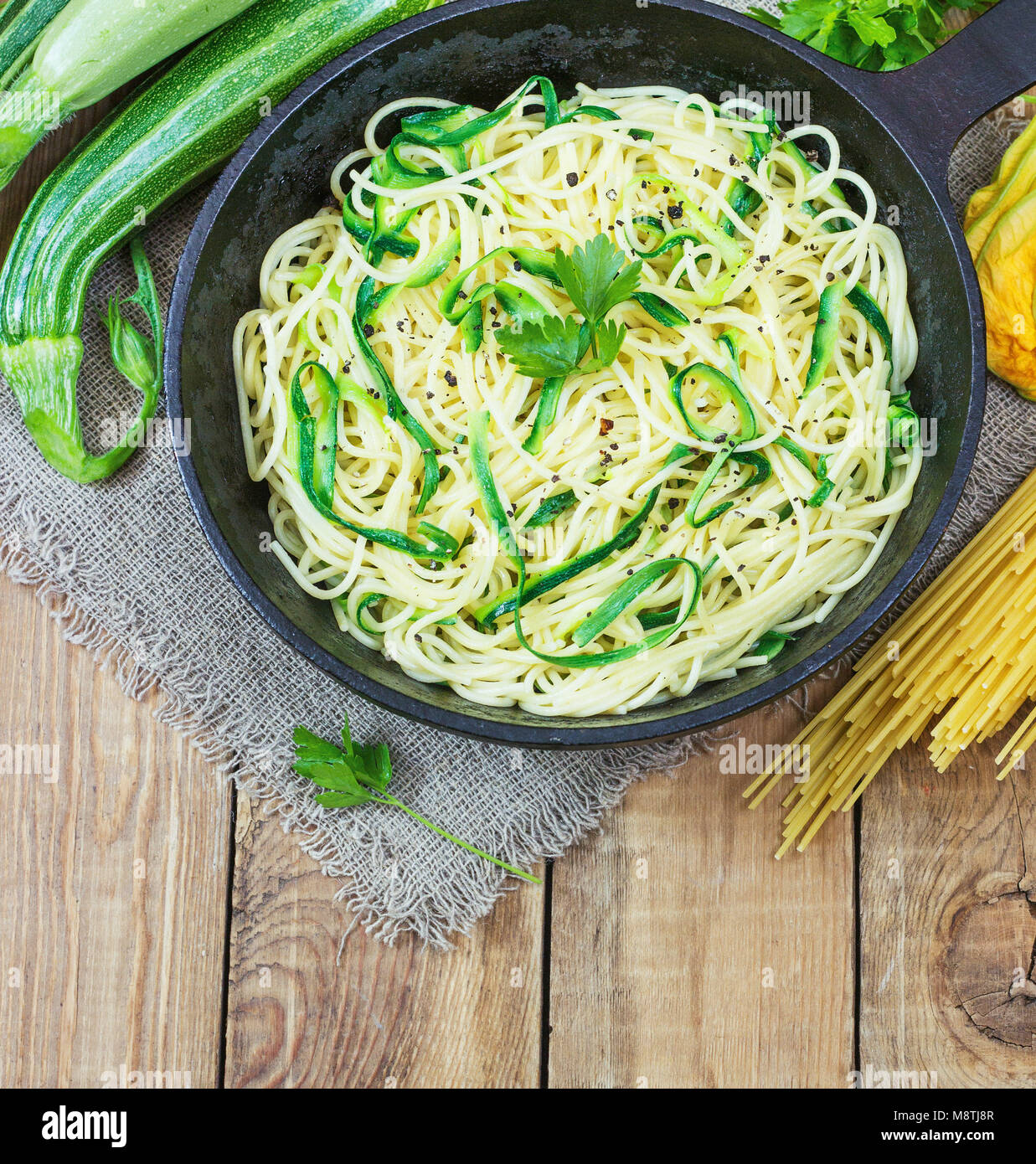 Pasta con le zucchine sul legno scuro in background di ghisa padella . Spaghetti da agricoltura biologica farine integrali. Foto Stock