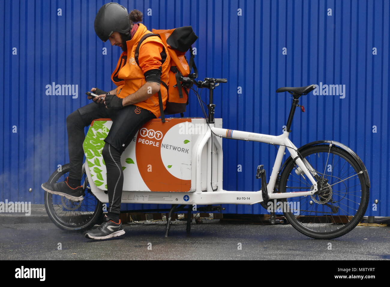La consegna di pacchi lavoratore sul suo cargo bike consultando il suo smartphone Torino Italia 8 Novembre 2017 Foto Stock