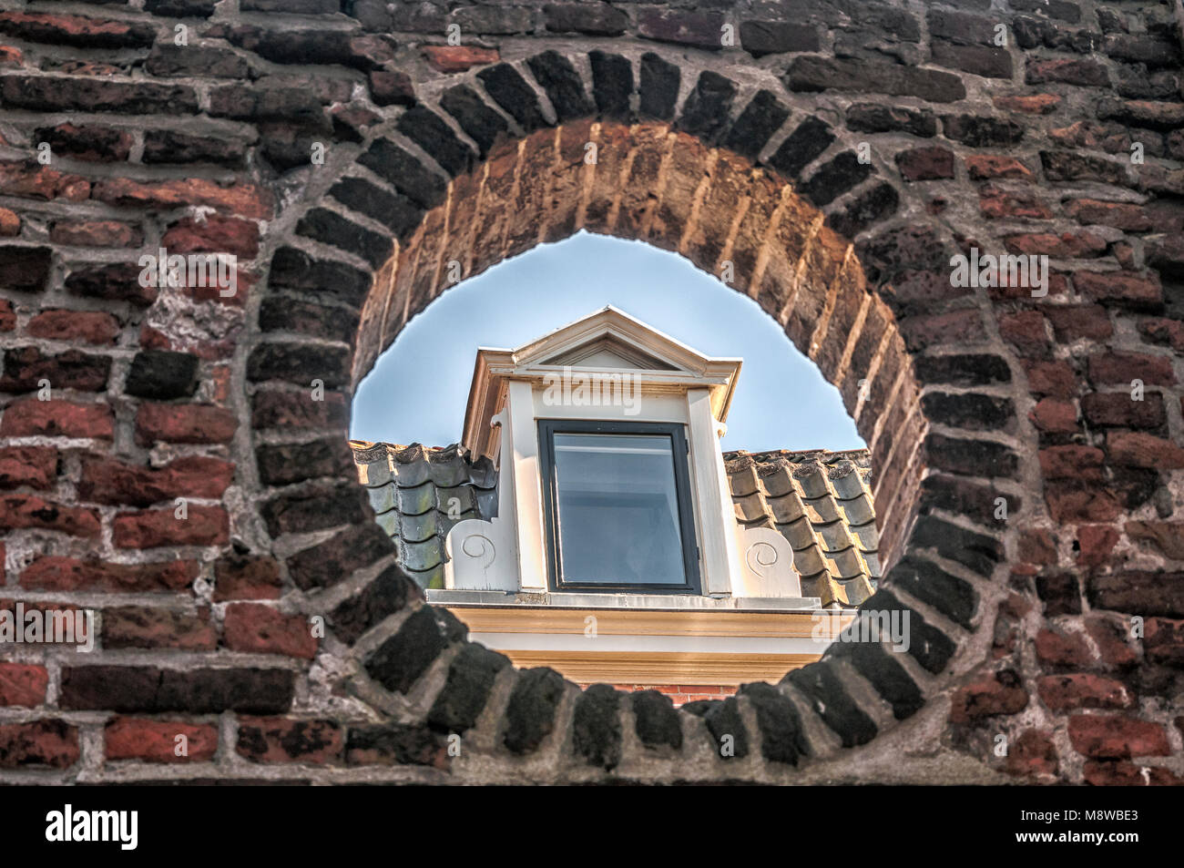 Abbaino di una vecchia casa fotografata attraverso un ovale apertura di parete Foto Stock