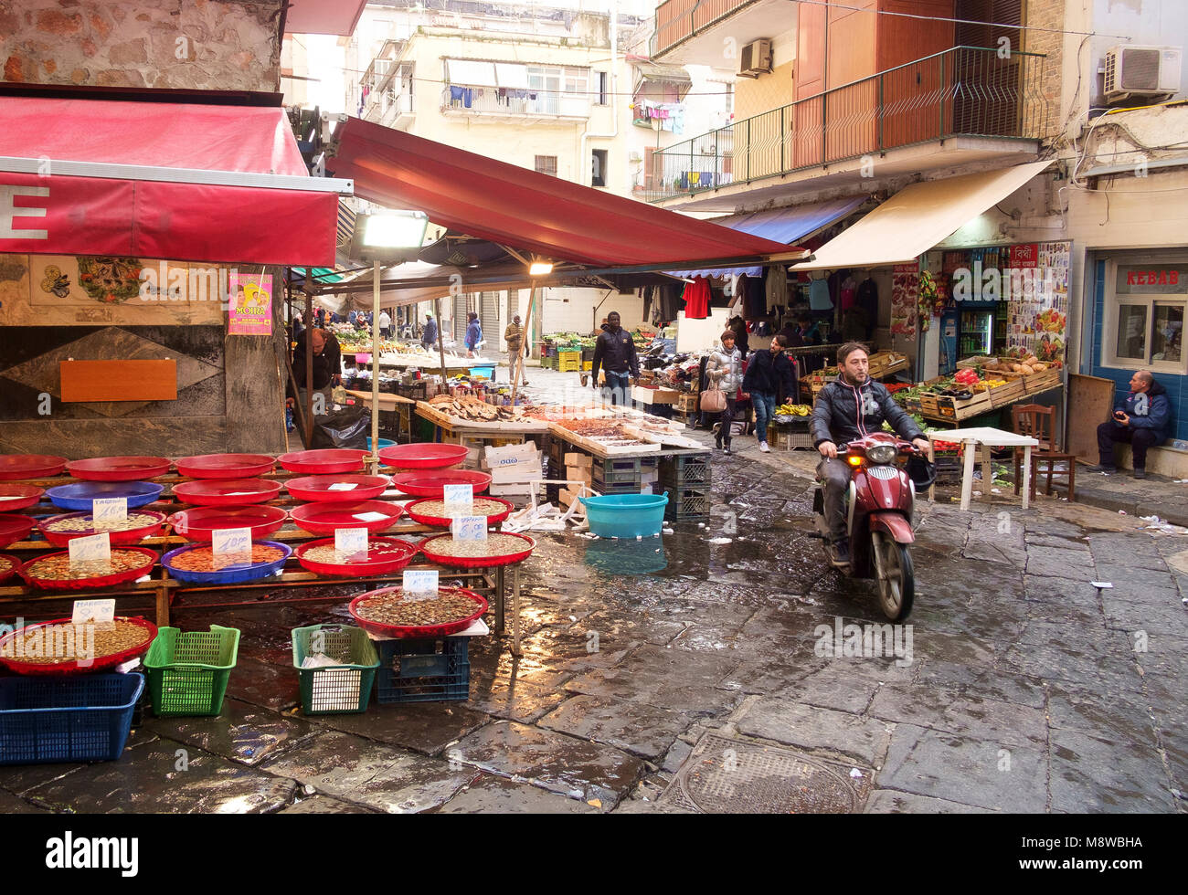 Un motore ciclista negozia Via Sopramuro - il mercato alimentare street vicino a Porta Nolana, Napoli Foto Stock