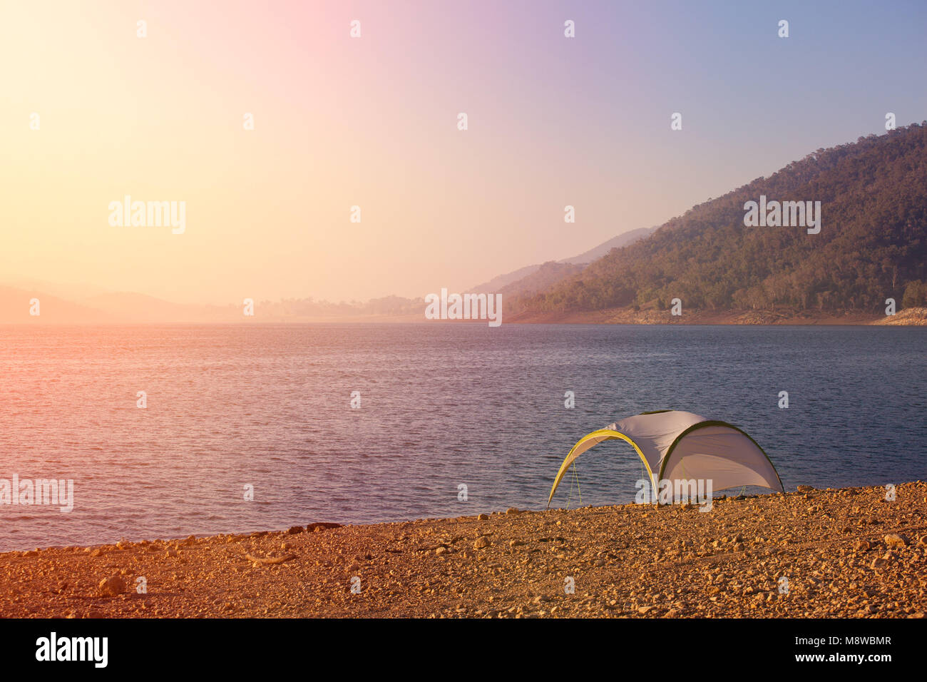 Lonely tenda in mountain lake shore a sunrise - tranquillo scena di meditazione Foto Stock