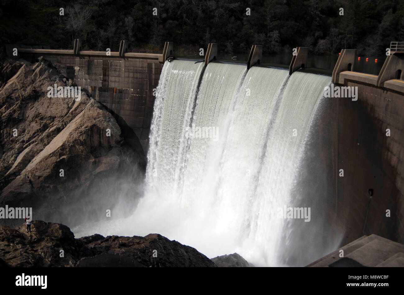 Una donna sola si inerpica lungo le rocce per ottenere una vista migliore della cascata a North Fork Dam. Foto Stock