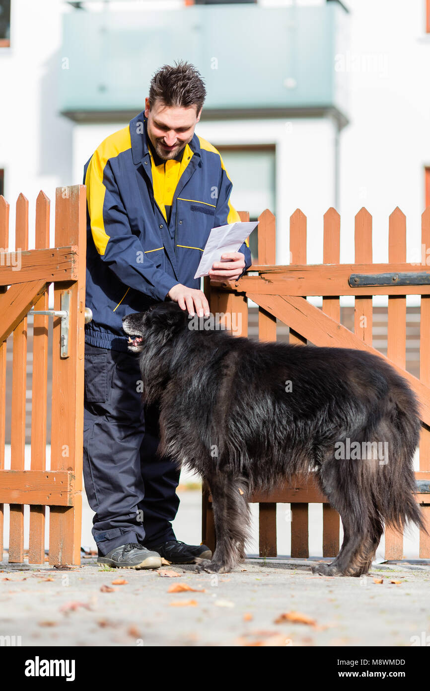 Grande cane nero accogliente il postino al cancello del giardino Foto Stock