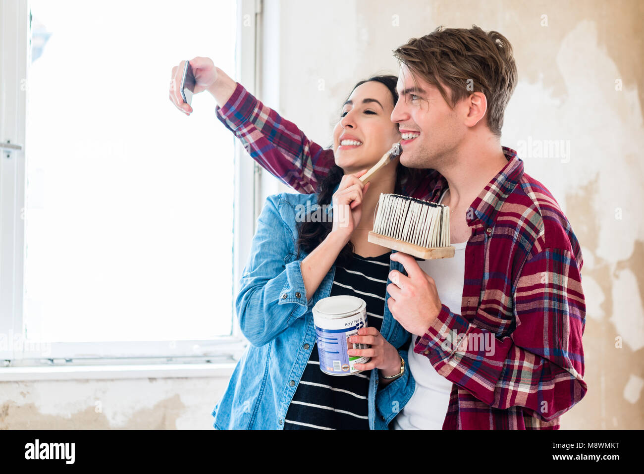 Coppia giovane facendo una selfie mentre si lavora per il rinnovo della loro casa Foto Stock