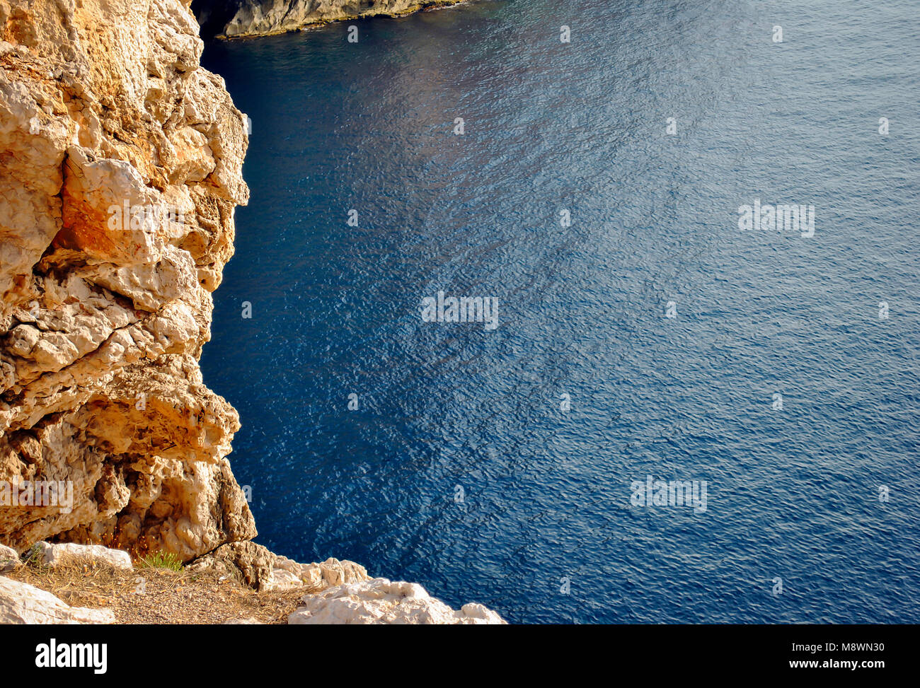 Costa rocciosa che si affaccia su un blu mare calmo in Sardegna, Italia Foto Stock