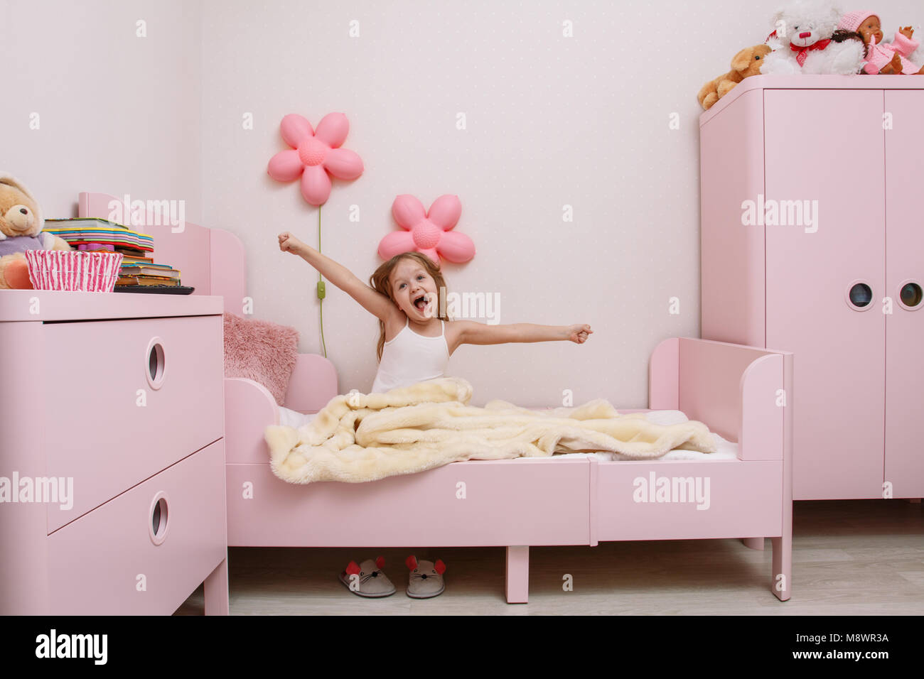 Piccola ragazza si sveglia al mattino in camera dei bambini Foto Stock