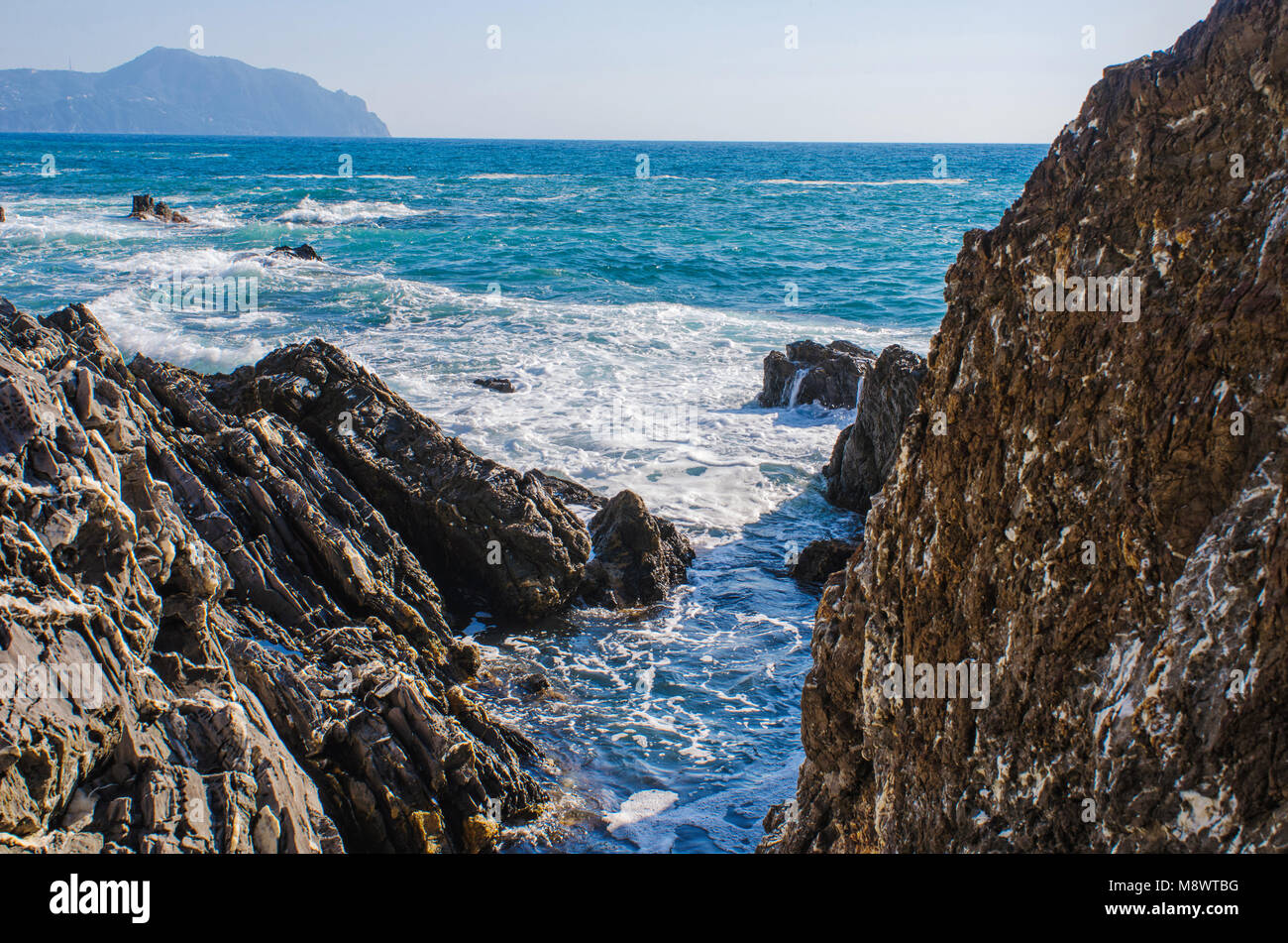 Piccolo torrente di acqua tra le scogliere di costa rocciosa del mare Mediterraneo a Genova Nervi, Italia, in vista dell'orizzonte e le montagne Foto Stock