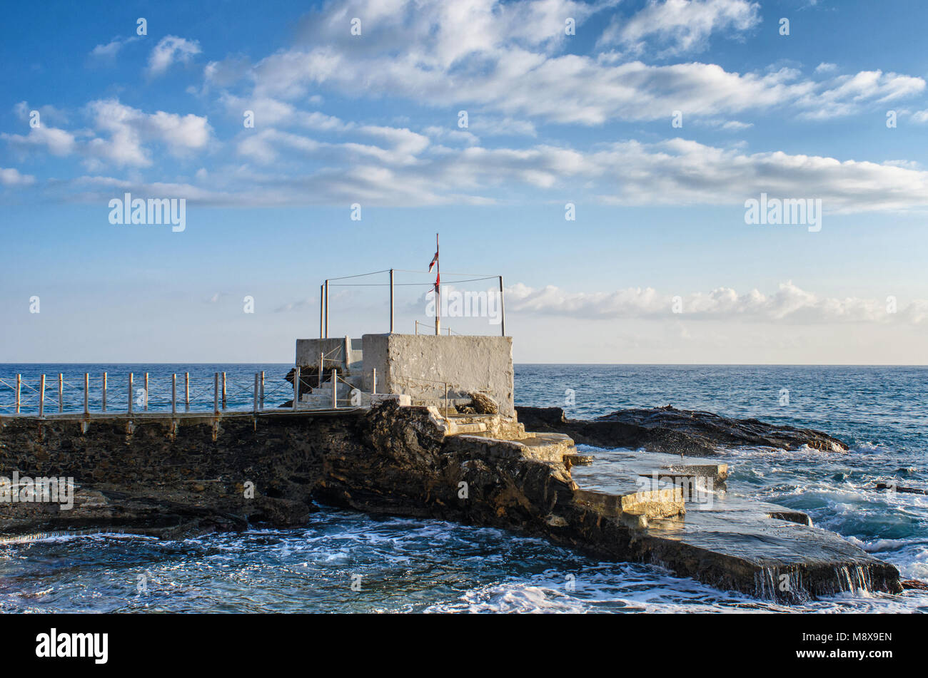 Pontile con una piattaforma rivolta verso la parte ligure del mar Mediterraneo su una bella giornata di sole a Genova Nervi sotto un cielo sereno con le nuvole Foto Stock