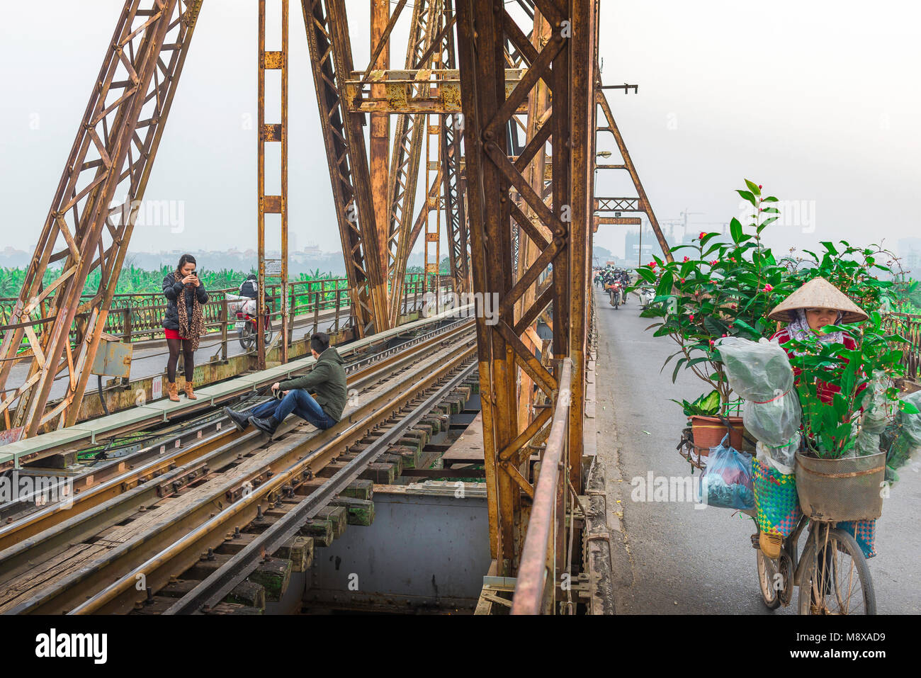 Hanoi lunga Bien Bridge, come ciclo di pendolari su lunghe Bien Bridge due giovani tappa una improvvisata foto-sparare sulla sua linea ferroviaria, Hanoi, Vietnam Foto Stock