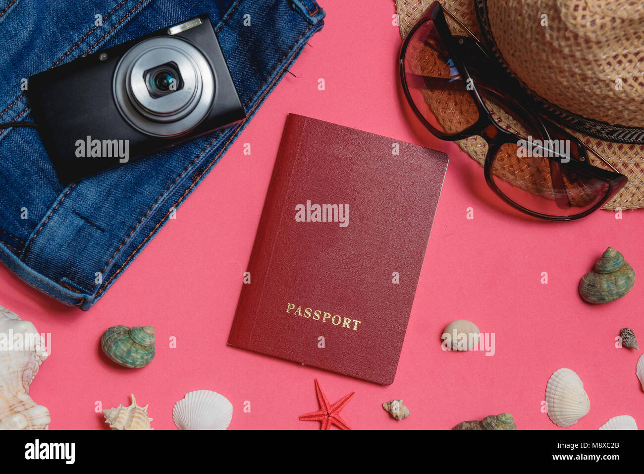 Passaporto, conchiglie, vestiti, occhiali da sole, Fotocamera, marrone cappello, su sfondo rosa Vista dall'alto concetto di viaggio Foto Stock