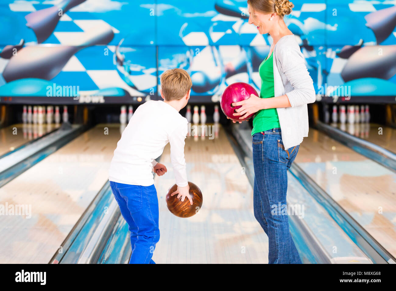 Madre e figlio insieme giocando a bowling center Foto Stock