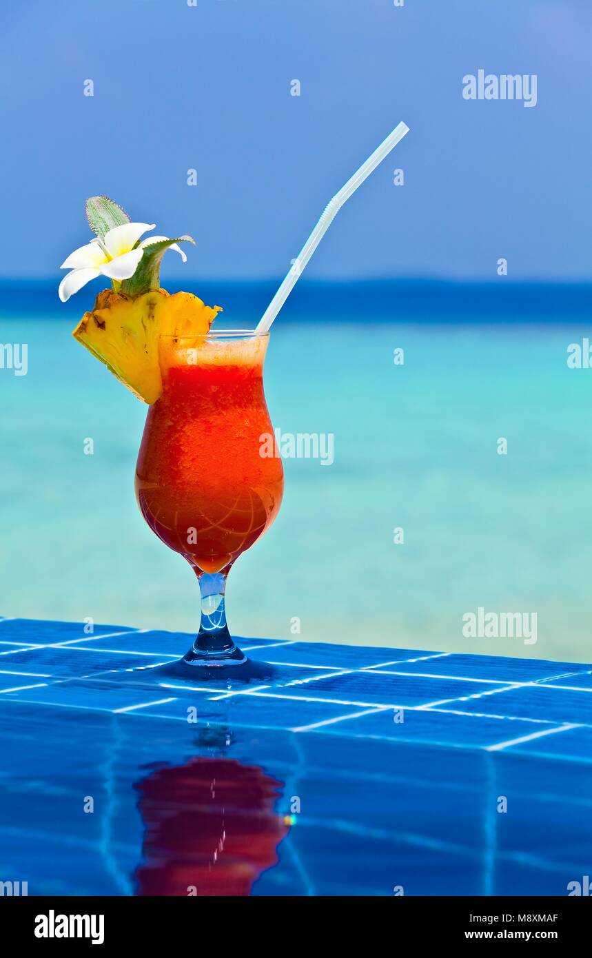 Bicchiere di succo papaw è sul bordo della piscina realizzato dalla piastrella vetrinata in hotel tropicale Maldive Foto Stock