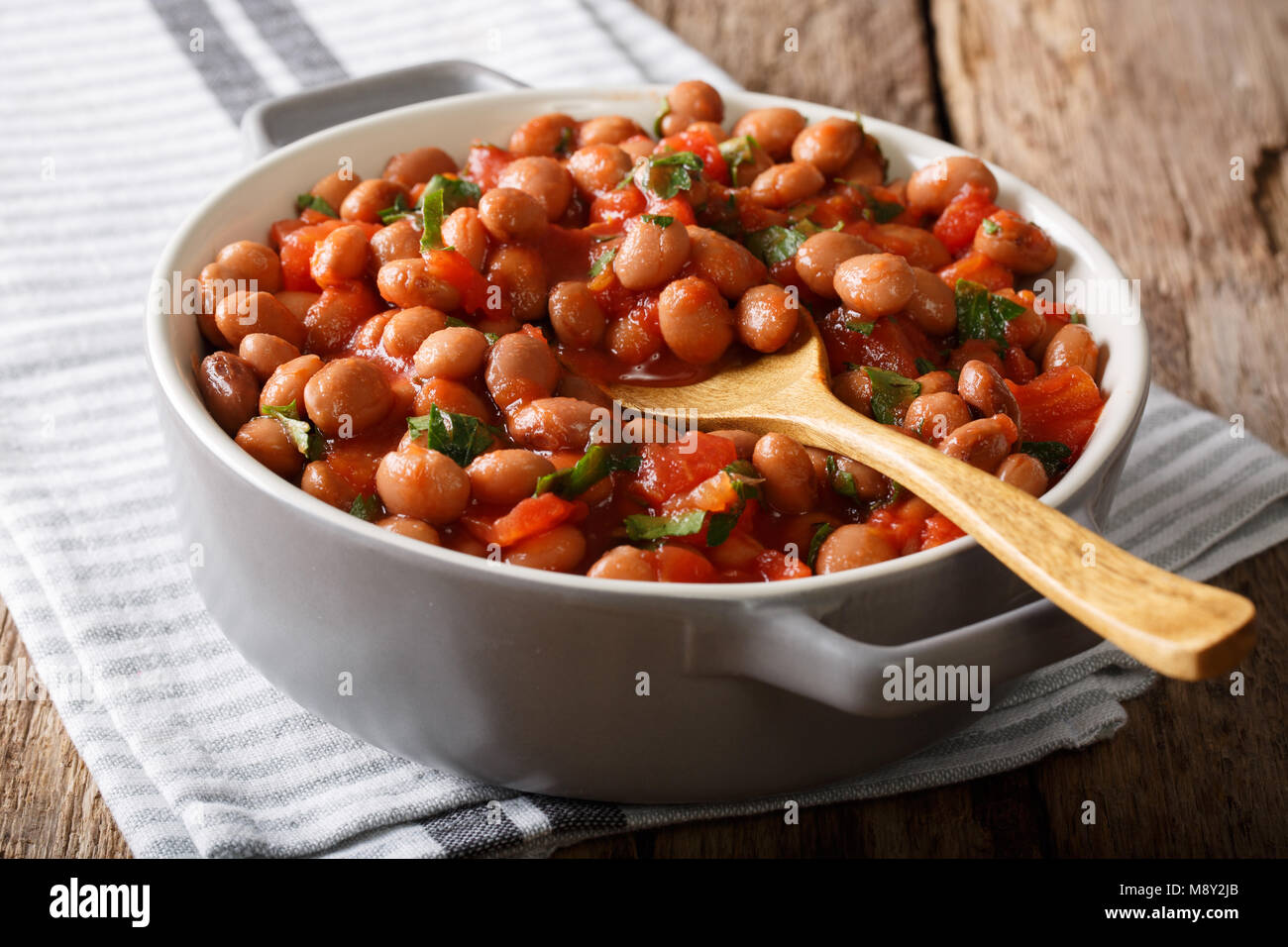 Cibo vegetariano fagioli borlotti in salsa di pomodoro con erbe di close-up in una ciotola sul tavolo orizzontale. Foto Stock