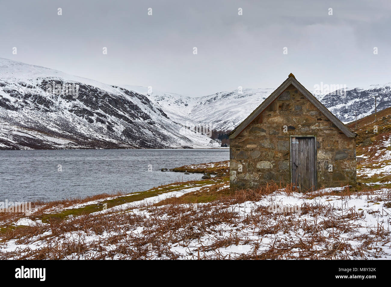 Un vecchio stile vittoriano Bothy di pesca oltre le sponde del Loch Lee in Angus Glens della Scozia, in una fredda e grigia giornata inverni. Foto Stock