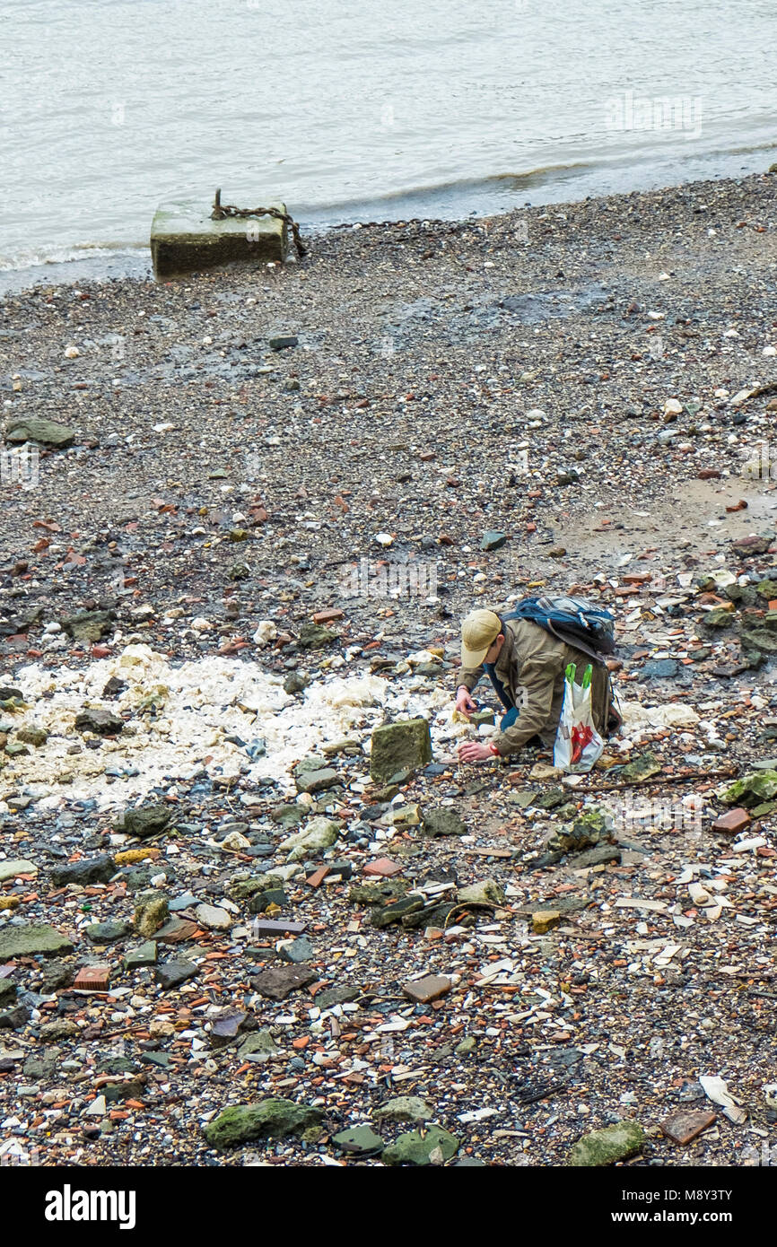 Un uomo In cerca e ricerca sull'foreshore del fiume Tamigi con la bassa marea. Foto Stock