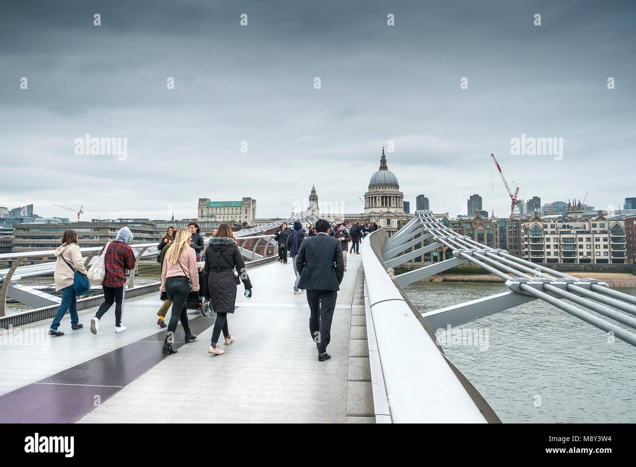 Pedoni che attraversano il Millenium Bridge di Londra in una fredda giornata a sopraggitto. Foto Stock