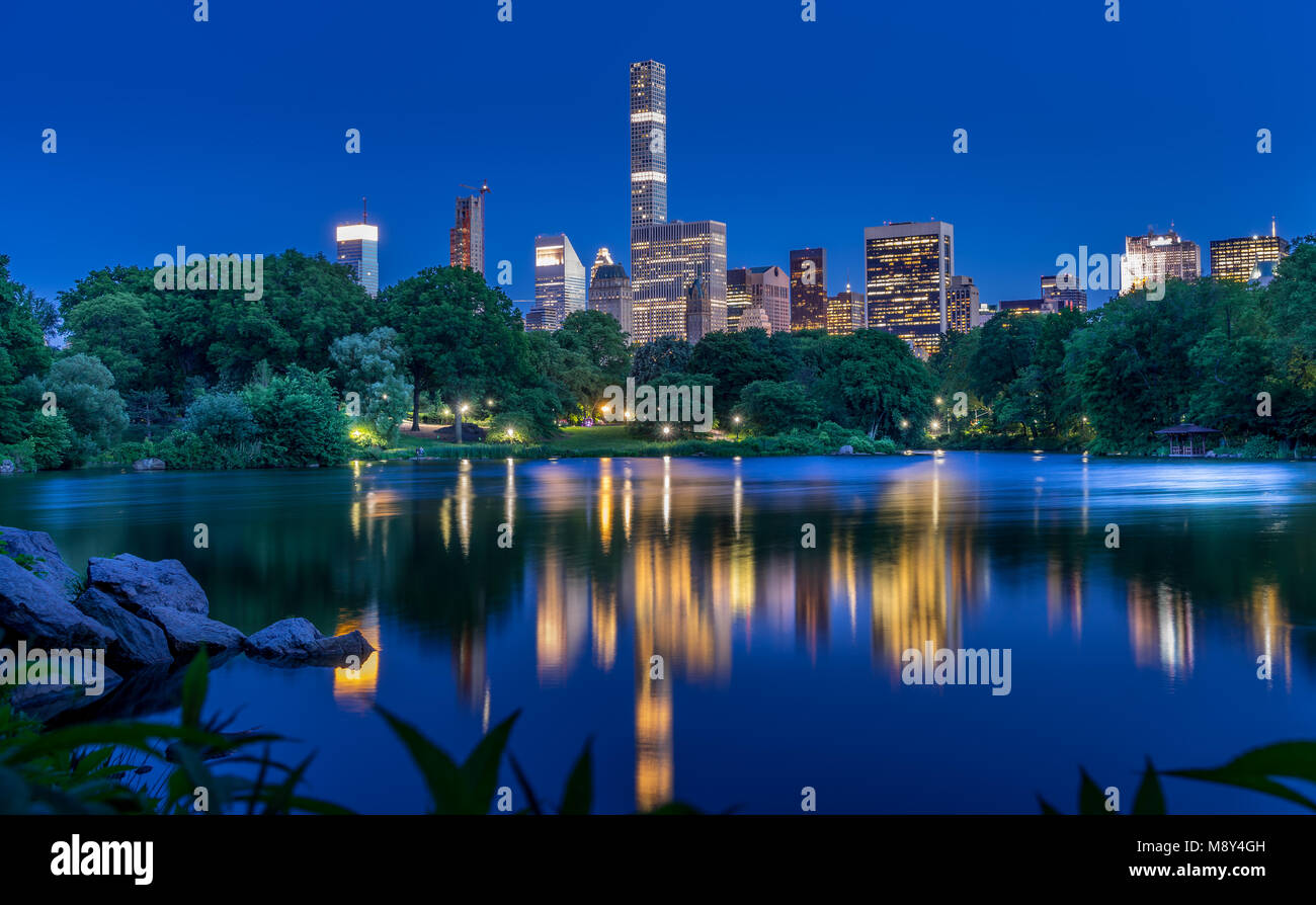 Skyline illuminata riflessa nel lago di Central Park di New York City Foto Stock