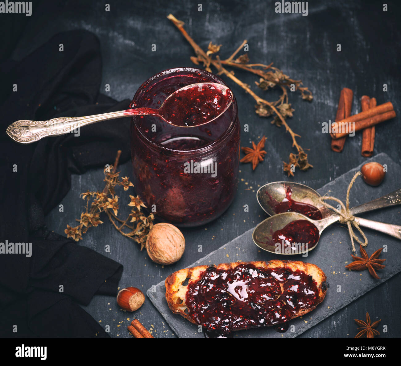 Confettura di lamponi in un vasetto di vetro con un cucchiaio di ferro, tonificazione vintage Foto Stock