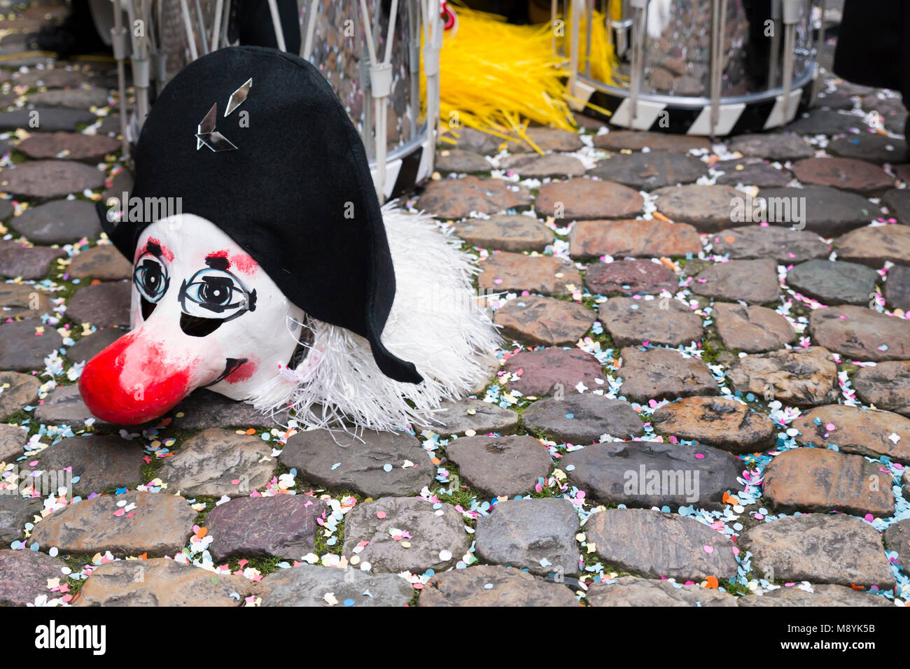 Il Carnevale di Basilea 2018. Andreasplatz, Basilea, Svizzera - Febbraio 19th, 2018. Close-up di una maschera di Carnevale e rullante su coriandoli strada coperta Foto Stock