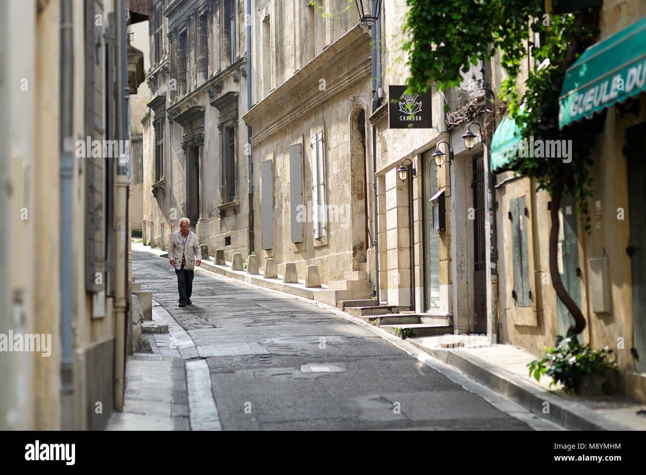 Il vecchio uomo locale a piedi al mattino presto su una stretta strada laterale nella parte vecchia di Arles. Francia Foto Stock