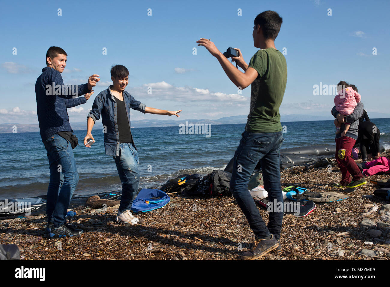 Afghan richiedenti asilo danza per la riproduzione di musica sui loro telefoni cellulari, celebrando il loro sicuro arrivo dopo aver attraversato il Mare Egeo. Nel 2015 più di un milione di immigrati arrivati in Europa dal mare. Gli immigrati sono principalmente di rifugiati che fuggono dalla guerra in Siria. Foto Stock