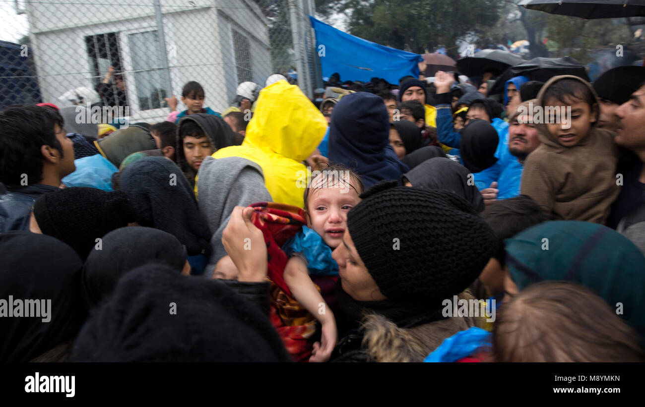 Centinaia di richiedenti asilo, comprese le donne e i bambini, attendere sotto la pioggia fredda di entrare Moria Camp, dove esse sono necessarie per la registrazione dopo l'arrivo in Grecia. Nel 2015 più di un milione di immigrati arrivati in Europa dal mare. Gli immigrati sono principalmente di rifugiati che fuggono dalla guerra in Siria. Foto Stock