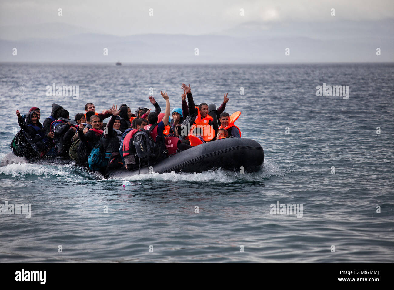 Richiedenti asilo celebrando dopo la traversata del mare Egeo dalla Turchia nel brutto tempo. Nel 2015 più di un milione di immigrati arrivati in Europa dal mare. Gli immigrati sono principalmente di rifugiati che fuggono dalla guerra in Siria. Foto Stock