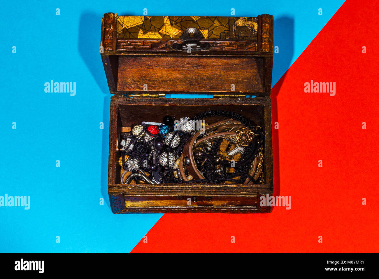 Antiquariato, cassa di legno con costume jewelery sulla colorata blu, sfondo rosso Foto Stock