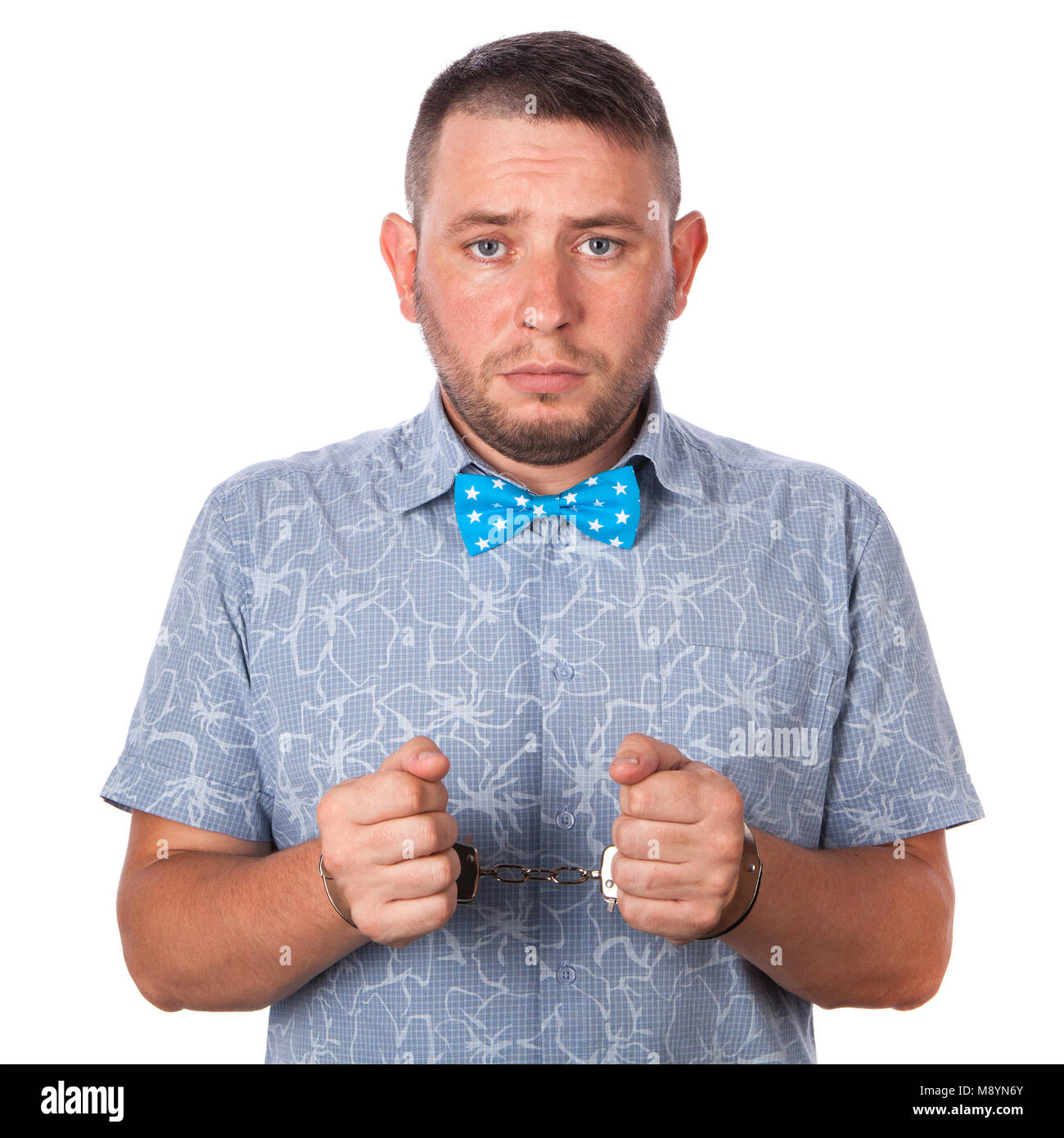 Maschio adulto con la barba in un blu bow tie in estate shirt in manette polizia isolato su uno sfondo bianco Foto Stock