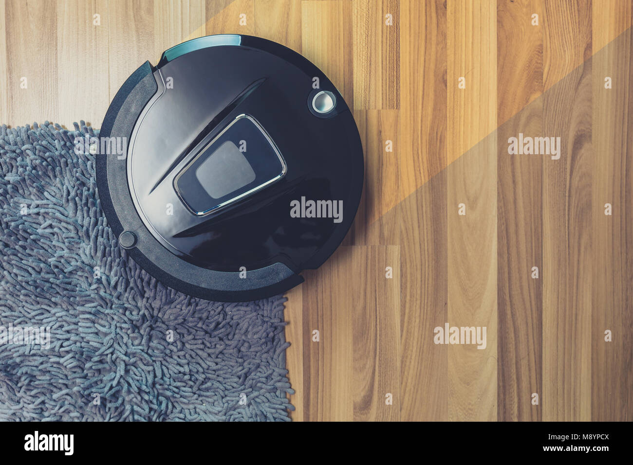 Robot aspirapolvere di pulizia sul polveroso pavimento in legno e moquette Foto Stock