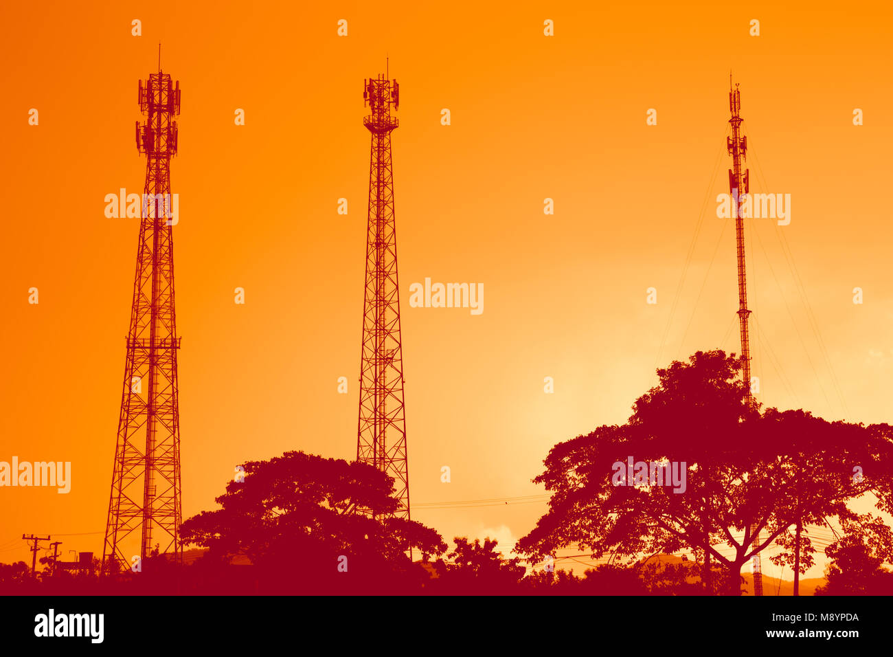 Silhouette di un segnale di telecomunicazione della torre radio sul cielo arancione Foto Stock