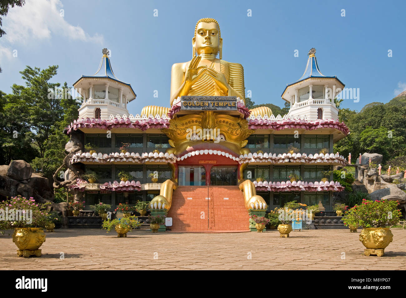 Il Golden Buddha sulla sommità del tempio d'Oro di Dambulla, Sri Lanka, in una giornata di sole con cielo blu. Foto Stock