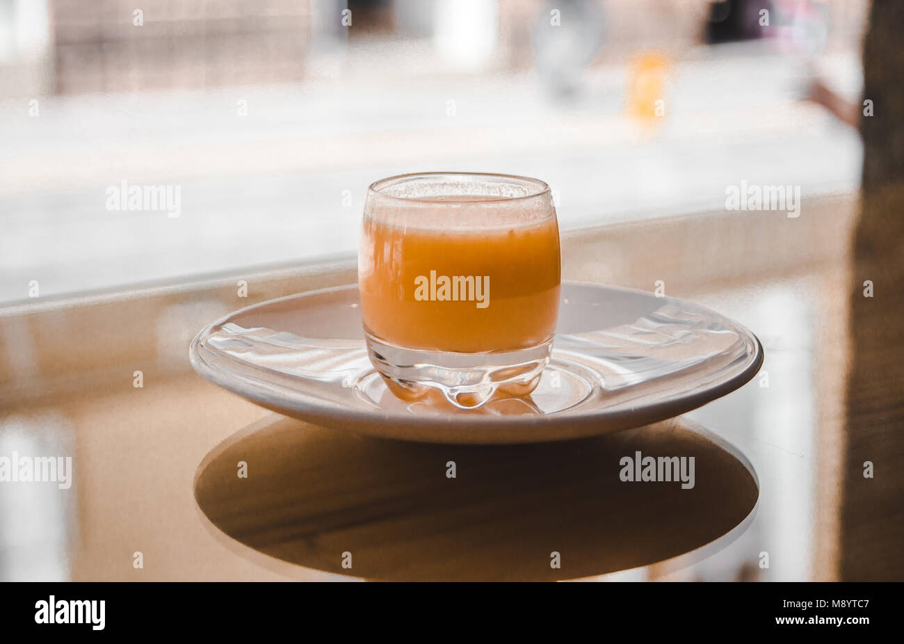 Un sano colpo di organico funzionale, di frutta e di ortaggi spice in un piccolo bicchiere su un piattino bianco nella finestra luminosa di una barra della salute Foto Stock