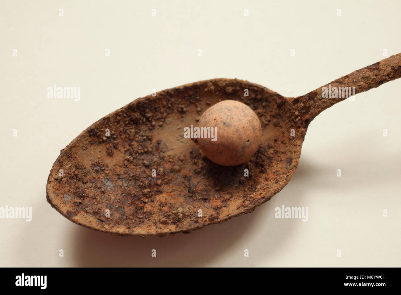 Close up di un cucchiaio arrugginito tenendo un marmo di argilla. Foto Stock