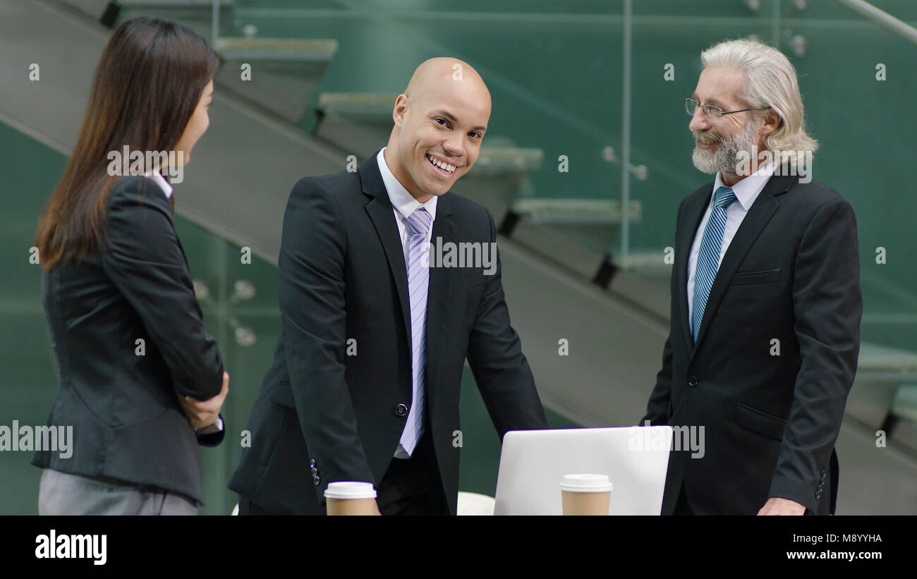 Giovani di successo corporate executive elogiato dal boss guardando la fotocamera e sorridente. Foto Stock