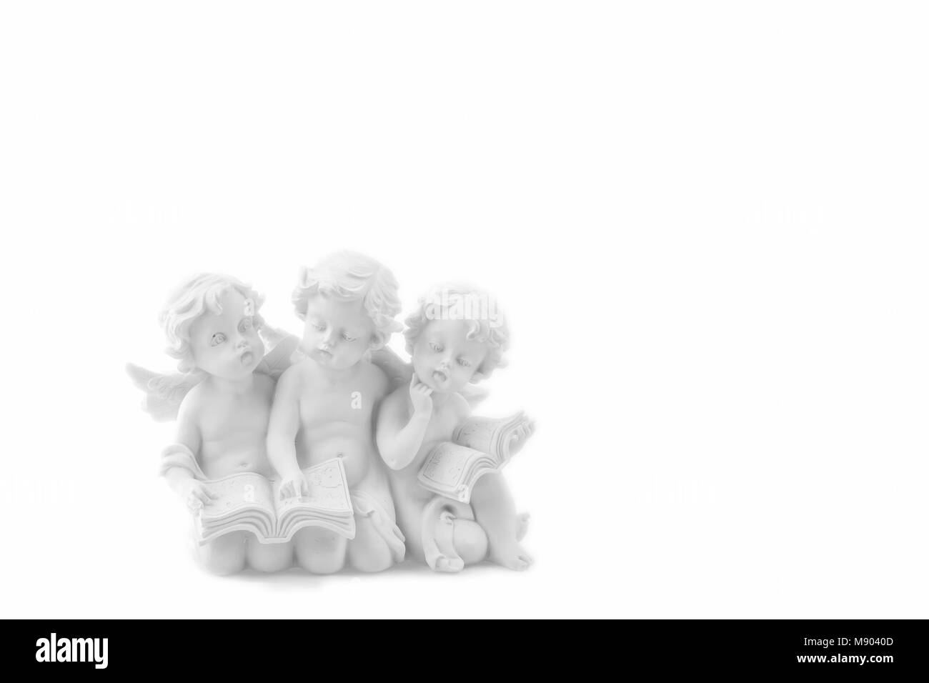 Tre ceramic white angeli leggere il libro, sognare e pensare. Isolato su bianco. Foto Stock