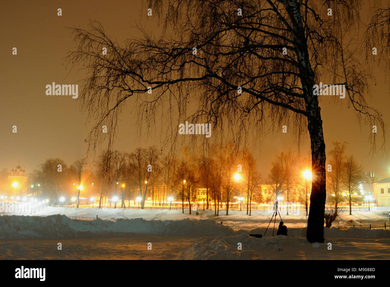Argine di piccola città è illuminato da lampioncini a notte invernale, un fotografo il treppiede è sul primo piano, Uglich, Yaroslavl Regione, Russia Foto Stock