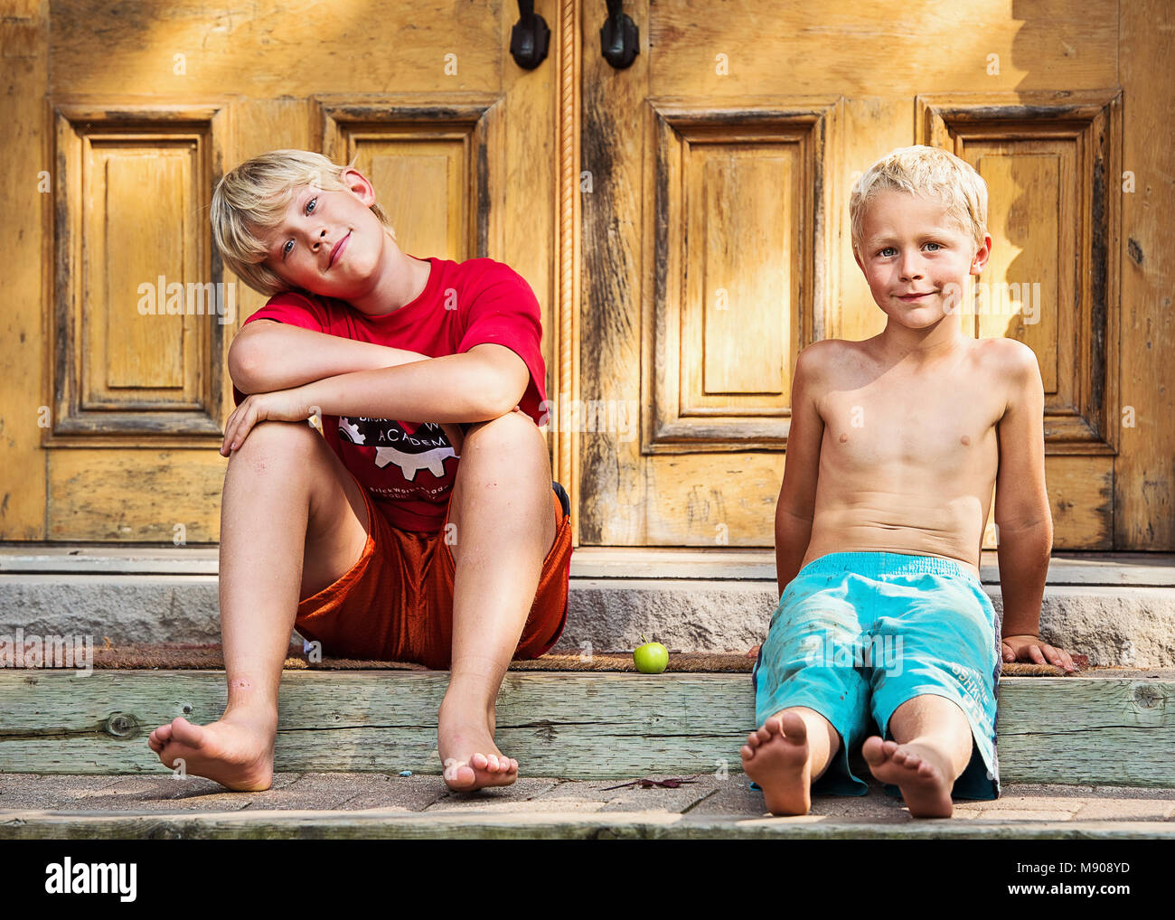 Fratelli seduta dalla porta in estate Foto Stock
