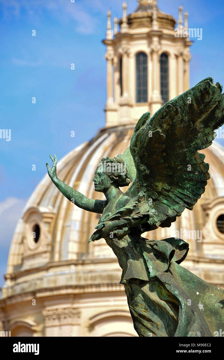Statua di donna alata (Victor Emmanuel monumento) contro delle cupole della chiesa di Santa Maria di Loreto Foto Stock