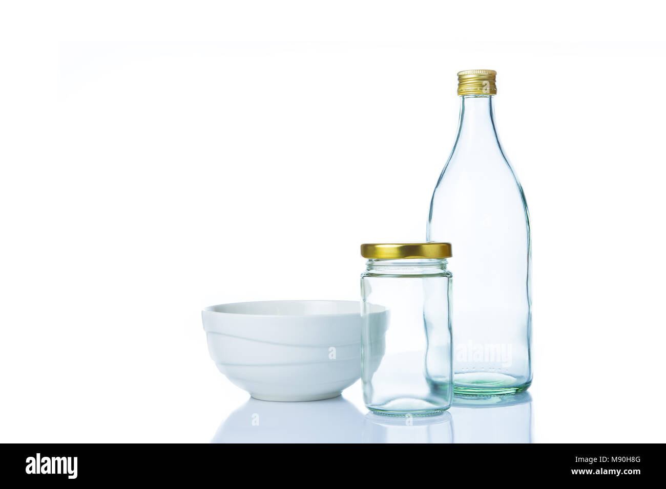 Vuoto cancellare le bottiglie di vetro in varie dimensioni e forme con coperchi e un bianco vaso in ceramica su sfondo bianco Foto Stock