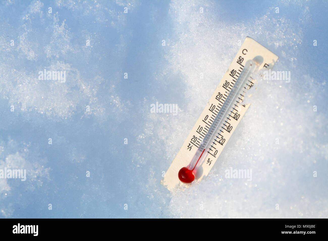 Il vetro della lampadina termometro giacente sulla neve con uno sfondo con spazio di copia Foto Stock